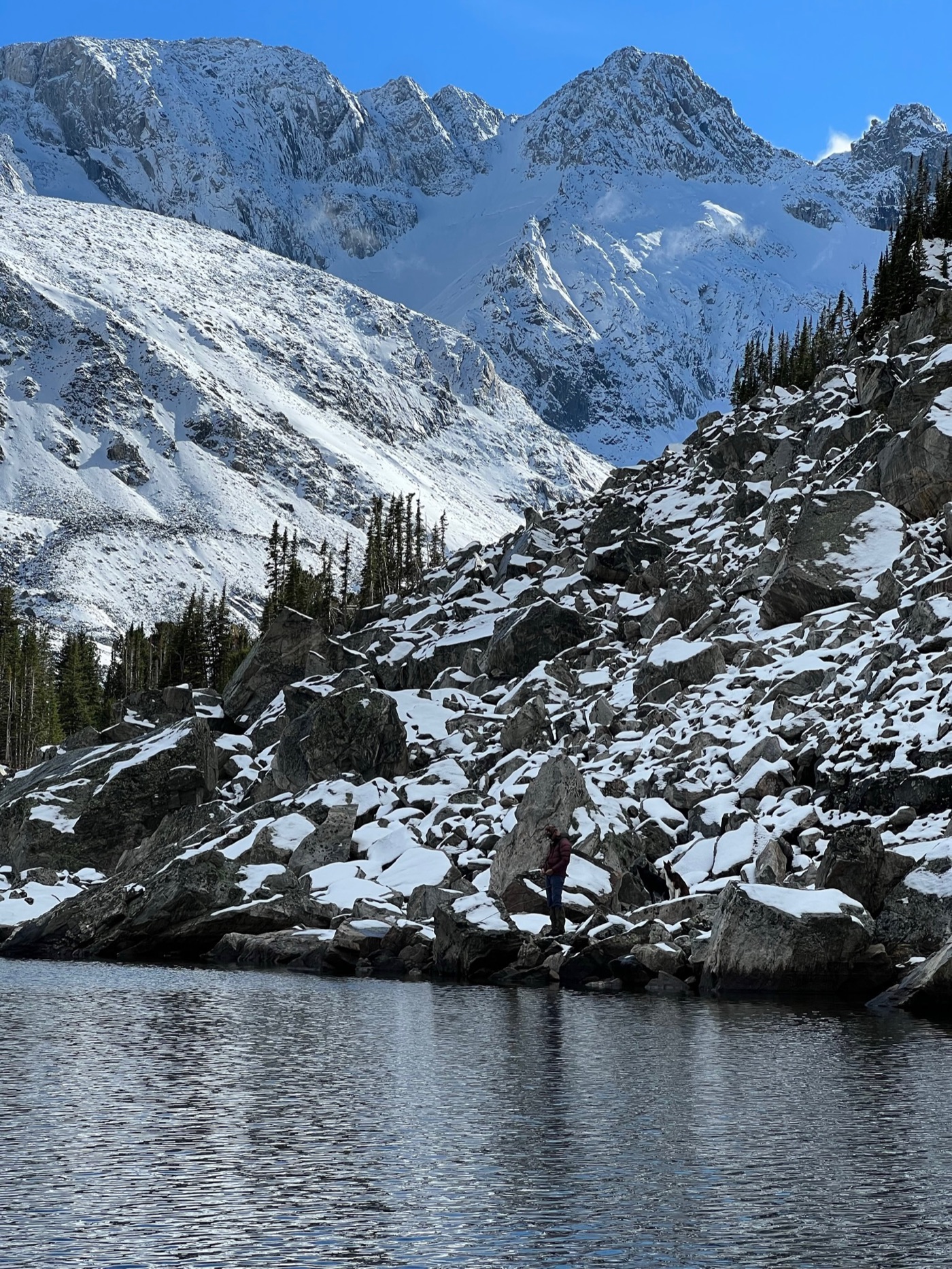 Snow-covered boulder field above an alpine lake