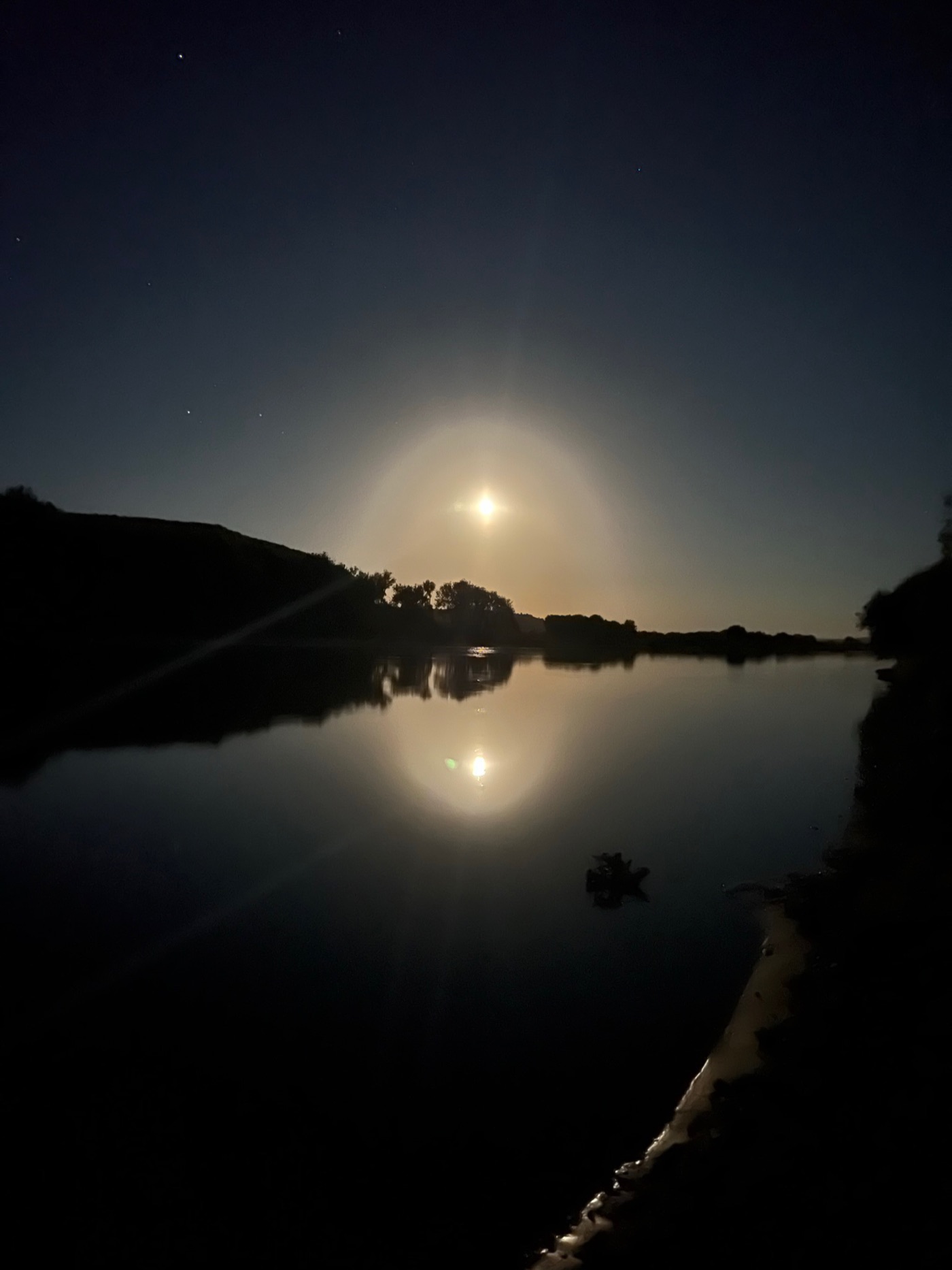 Moonrise reflected on a still river at night