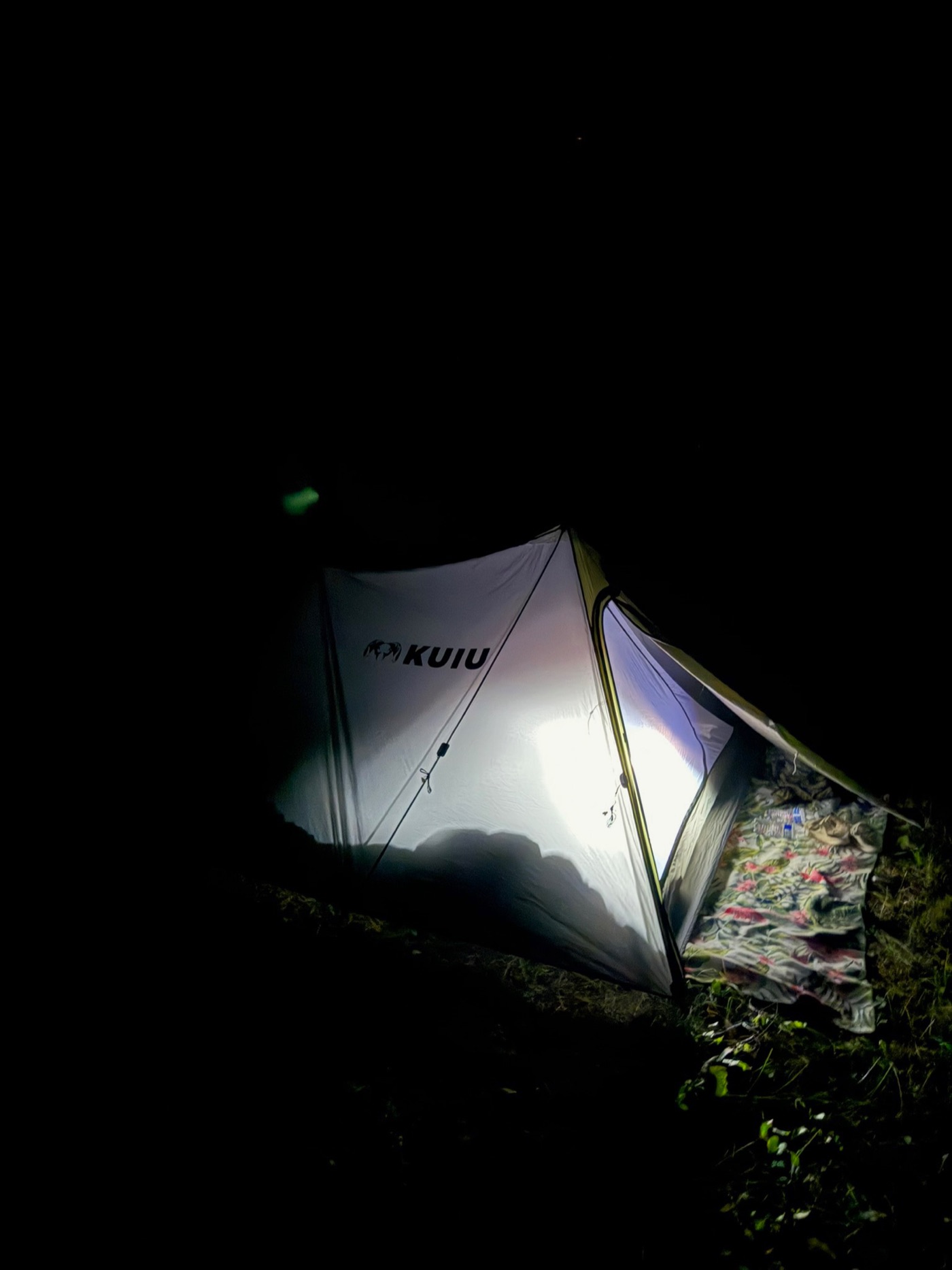 The KUIU tent glowing from inside at night — the tent from the story